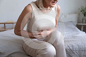 Unhealthy woman embracing belly, suffering from strong stomach ache.