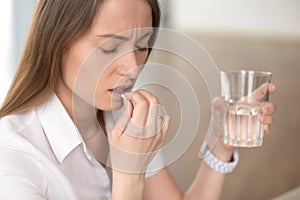 Unhealthy woman feeling migraine headache, taking pill medicatio