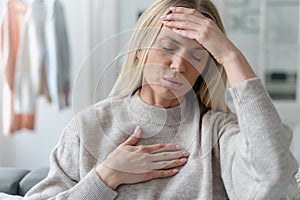 unhealthy woman in fever touching forehead and chest