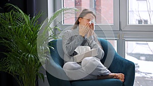Unhealthy woman sits in a chair and coughs because she has a cold, flu