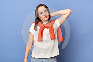 Unhealthy woman wearing white t-shirt and jumper over neck standing isolated over blue background feeling fatigue touching painful