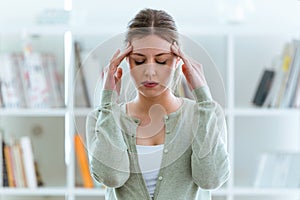 Unhealthy young woman with headache touching his head at home.