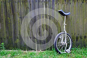 Unibike monocycle standing against wooden fence background