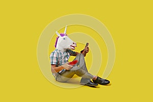 Unicorn man is on the phone sitting on the floor