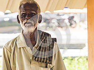 An unidentifed old senior indian poor man portrait with a dark brown wrinkled face and white hair and a white beard, looks serious