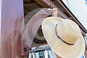 Unidentifiable man in a sunhat staining wood photo