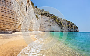 Unidentifiable tourists on a beautiful wild beach in Puglia, Italy, famous touristic destination in Europe. Tourists came with a