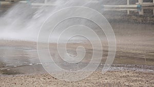 Unidentified asian worker using a powerful hose sprayer from a tanker truck to wash the road