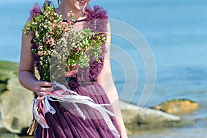 Unidentified bride in beautiful wedding dress holding gentle nice bridal bouquet with fresh blooming flowers, outdoors