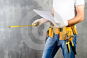 Unidentified builder standing in white gloves with a tool belt w