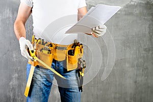 Unidentified builder standing in white gloves with a tool belt w
