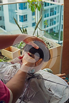 Unidentified child getting haircut at the apartment home balcony