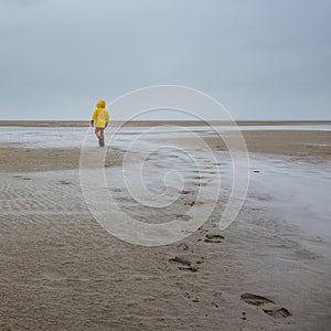 Unidentified child in oilskin jacket on deserted beach