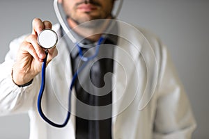 An unidentified doctor grabs a stethoscope to the camera to check the patient