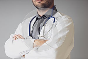 An unidentified doctor with a stethoscope around the neck crosses his arms