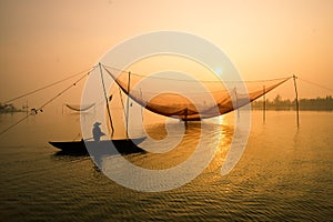 Unidentified fisherman checks his nets in early morning on river in Hoian, Vietnam