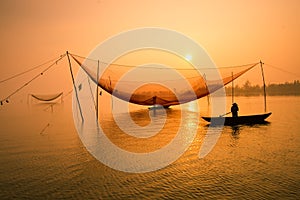 Unidentified fisherman checks his nets in early morning on river in Hoian, Vietnam