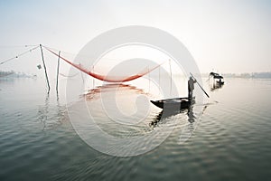 Unidentified fisherman checks his nets in early morning on river in Hoian, Vietnam