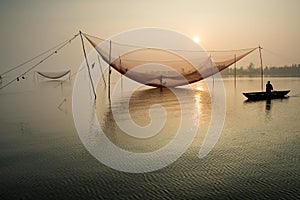 Unidentified fisherman checks his nets in early morning on river in Hoian, Vietnam photo