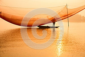 Unidentified fisherman checks his nets in early morning on river in Hoian, Vietnam photo