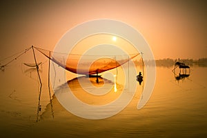 Unidentified fisherman checks his nets in early morning on river in Hoian, Vietnam