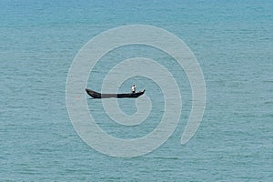 Unidentified Ghanaian man sails in canoe in Atlantic ocean.