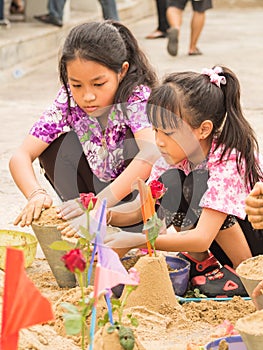 Unidentified girls making sand pagodas with colorful flags in So