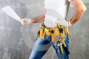 Unidentified handyman with hand on waist and tool belt with cons