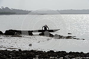 Unidentified local man stands near the boat on the coast of the