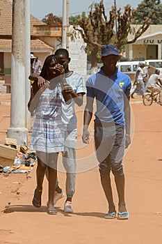 Unidentified local people walk along the road in the centre of