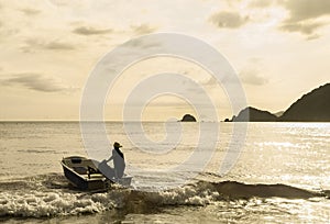 An unidentified man drives boat during sunset in Praia Do Sono, Paraty, Brazil photo