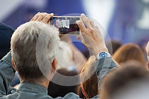 Unidentified man filming scene by mobile phone during a concert dedicated Moscow city day on September 9, 2019