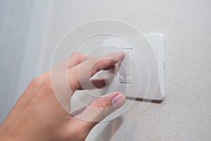 Unidentified man hand with finger on light switch turn on turn off lights.
