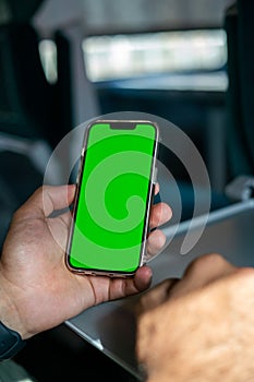 Unidentified man holding a smartphone with green screen