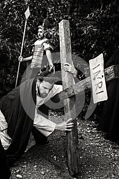 Unidentified man portraying Jesus Christ carries large wooden cross during reenactment of the Crucifixion. Black and White