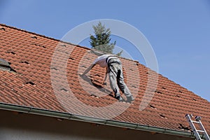 An unidentified man is preparing the roof for the installation of solar panels. the roof of a family house with red tiles