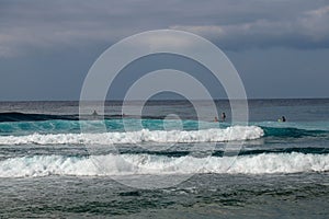 Unidentified man on surf board waiting for wave in blue water back view. Young Boys Waits the Waves. Surfer waiting in line for a