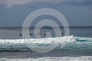 Unidentified man on surf board waiting for wave in blue water back view. Young Boys Waits the Waves. Surfer waiting in line for a