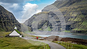 Unidentified man walking towards church from village of Saksun, Faroe Islands, Denmark