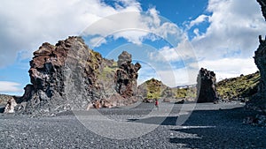 Unidentified man walking in volcanic lava rocks at Djupalonssandur beach in Snaefellsnes peninsula in Western Iceland