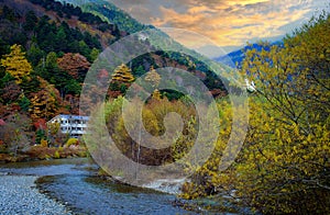 the unidentified mountain resort hotel in the background of Azusa river and colorful autumn trees at Kamikochi, Nagano pref.