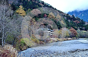 the unidentified mountain resort hotel in the background of Azusa river and colorful autumn trees at Kamikochi, Nagano pref.