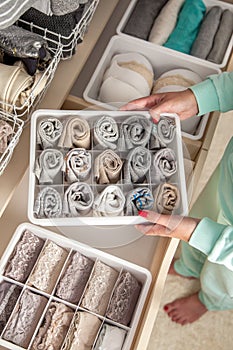 Unidentified neat housewife puts container with socks, panties and underwear. Clothes storage.