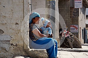 An unidentified Nepalese woman with a small child on her knees sits against the wall of a house on Jomsoma Street. Nepal