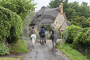 Unidentified people and horses near cottages in the village of Stanton, Cotswolds district of Gloucestershire.