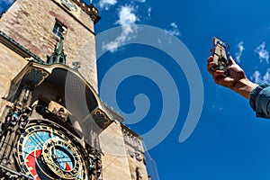 Unidentified person with a smartphone in the hand takes pictures of the astronomical clock in Prague