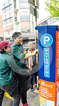 Unidentified persons using the parking ticket payment machine at the side of the road