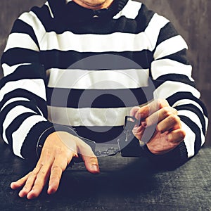 Unidentified prisoner in prison stripped uniform sitting in hand