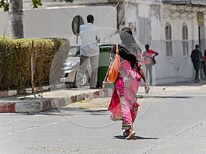 Unidentified Senegalese woman walks along the street in the cen