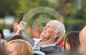 Unidentified senior man filming scene by mobile phone during a concert dedicated Moscow city day on September 9, 2019